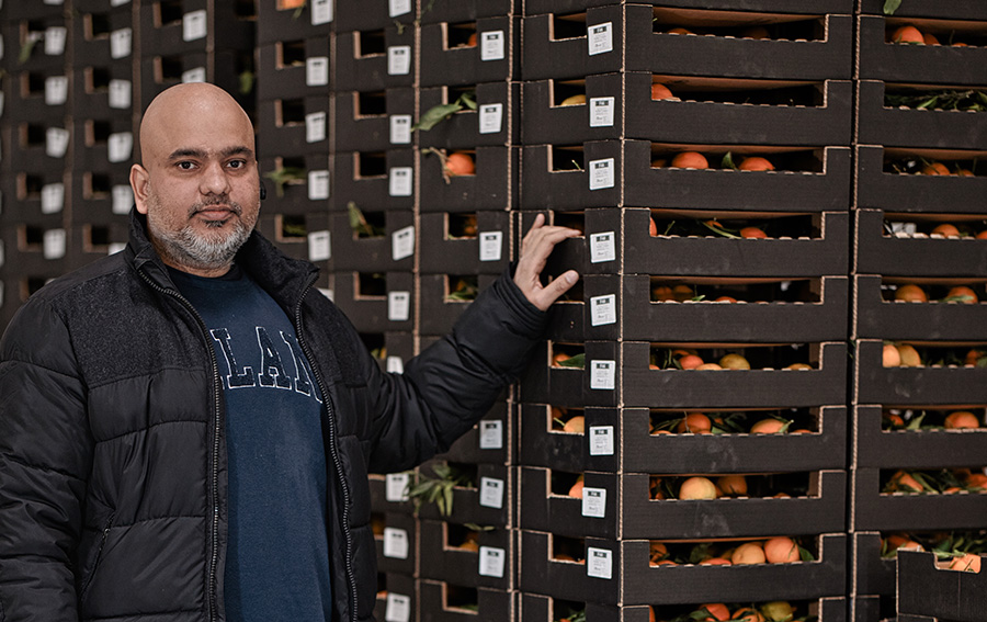 A Sublog employee standing beside pallets of fruits in a warehouse.
